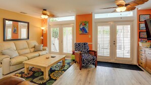 Ein Wohnzimmer mit Sofa, Sesseln, Couchtisch und Deckenventilator.