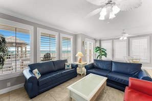 Ein Wohnzimmer mit zwei blauen Sofas, einem Couchtisch und einem Deckenventilator.