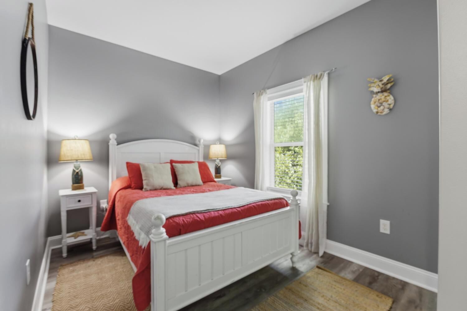 A bedroom with a bed, nightstands, a window, and a wall decoration.