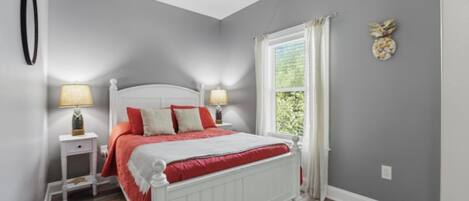 A bedroom with a bed, nightstands, a window, and a wall decoration.
