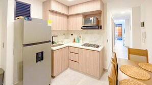 Cozinha compacta com geladeira, micro-ondas, pia e armários de madeira.