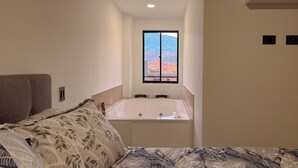 Um quarto com cama, janela e banheira.