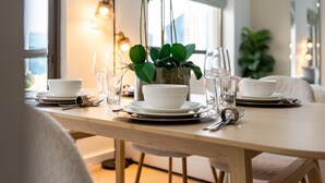 A dining table set with white bowls, plates, and cutlery, a vase with white flowers, and a potted plant. - Balcony Overlooking the Marina and Yachts, Near the Tram Station and Mall (Dubai)