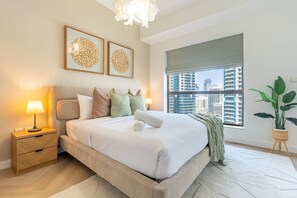 A modern bedroom with a bed, bedside table, lamp, artwork, window, and potted plant. - Balcony Overlooking the Marina and Yachts, Near the Tram Station and Mall (Dubai)