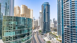 A modern urban skyline with high-rise buildings, a curved glass structure, and a multi-lane road. - Balcony Overlooking the Marina and Yachts, Near the Tram Station and Mall (Dubai)