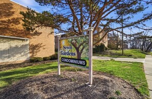 A sign for 'Seven Gardens Condominiums' with a tree illustration.