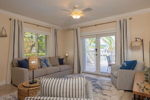 Ein Wohnzimmer mit einer Couch, einem Sessel und einem Deckenventilator.