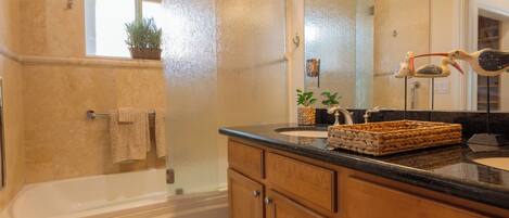 A bathroom with a bathtub, a sink, wooden cabinets, a mirror, and a window with a plant.