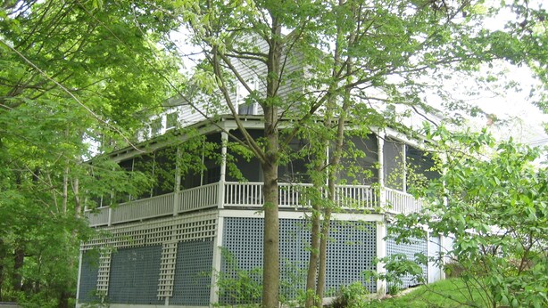 Ein mehrgeschossiges Gebäude mit einem Balkon, umgeben von üppiger Vegetation und einer Treppe, die dorthin führt.