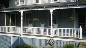Ein zweistöckiges Haus mit Veranda, weißen Geländern und hängenden Blumenkörben.