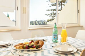 Ein Esstisch mit Croissants, Obst, einer Pellegrino-Flasche und einem Glas Orangensaft.