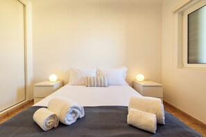 Quarto de hotel com uma cama bem arrumada, duas luminárias de cabeceira e uma janela.