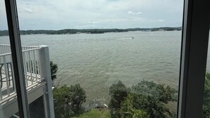 A view of a body of water with a boat, trees, and a distant shoreline. - Escape to this top floor,  pet-friendly 3BR/3BA condo at Regatta Bay MM 12 (Lake Ozark)