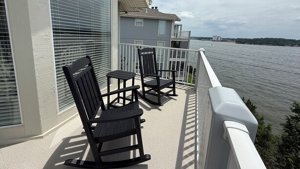 A balcony with two rocking chairs and a table, overlooking a body of water. - Escape to this top floor,  pet-friendly 3BR/3BA condo at Regatta Bay MM 12 (Lake Ozark)