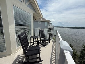 Ein Balkon mit zwei Schaukelstühlen und einem Tisch, mit Blick auf ein Gewässer.