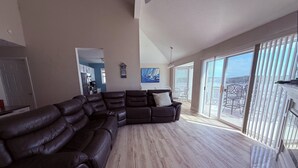 A spacious living room with a large sectional sofa, a dining area with chairs, and a view through large windows. - Escape to this top floor,  pet-friendly 3BR/3BA condo at Regatta Bay MM 12 (Lake Ozark)