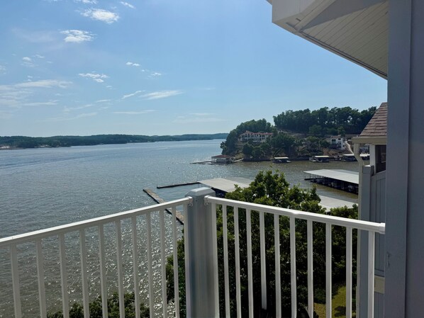 Un balcon avec vue sur un lac, des bateaux amarrés et des maisons situées sur une colline.