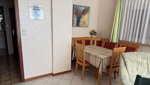 Un comedor con una mesa y sillas, un cuadro en la pared y una ventana con cortinas.