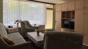 Una sala de estar con sofá, sillón, mesa y mueble para televisión.