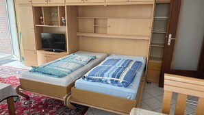 Un dormitorio con dos camas, televisión y almacenamiento integrado.