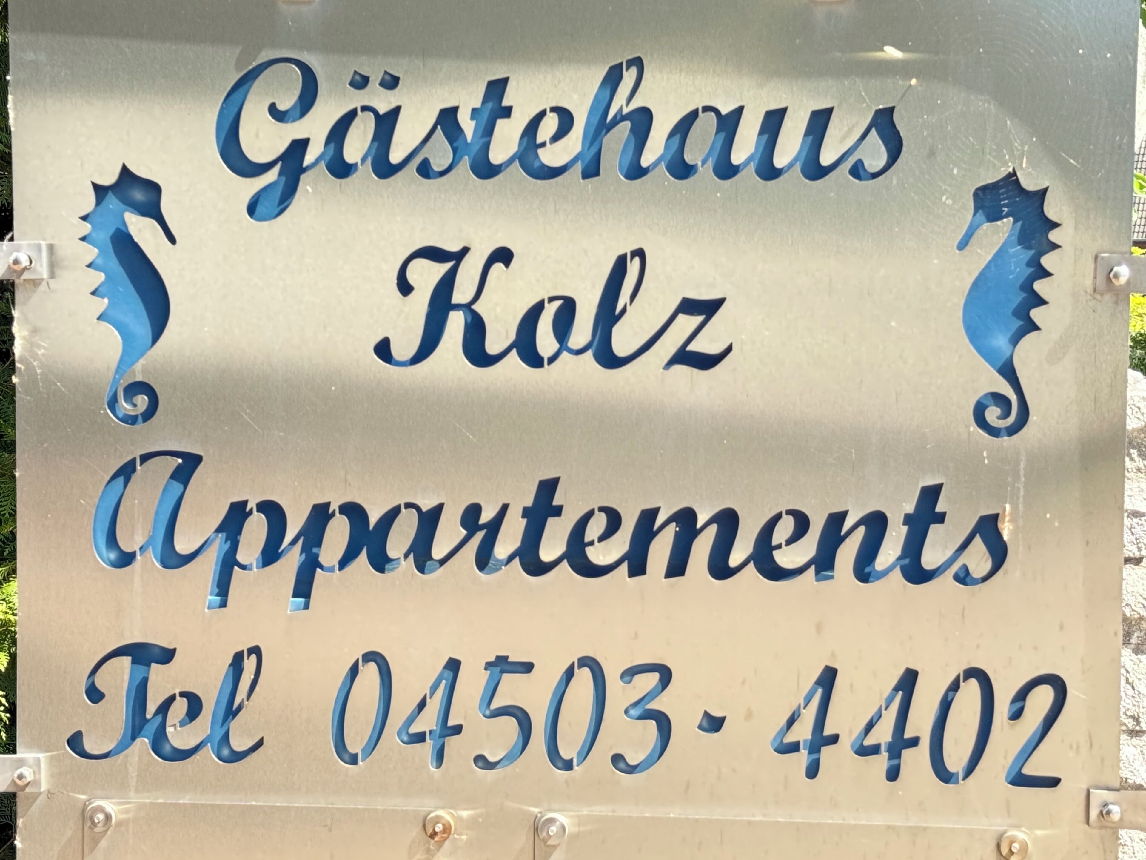 Une enseigne indiquant « Gästehaus Kolz Apartments » avec un numéro de téléphone à contacter.