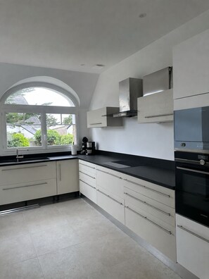 Eine moderne Küche mit weißen Schränken, einer schwarzen Arbeitsplatte und einem eingebauten Backofen.