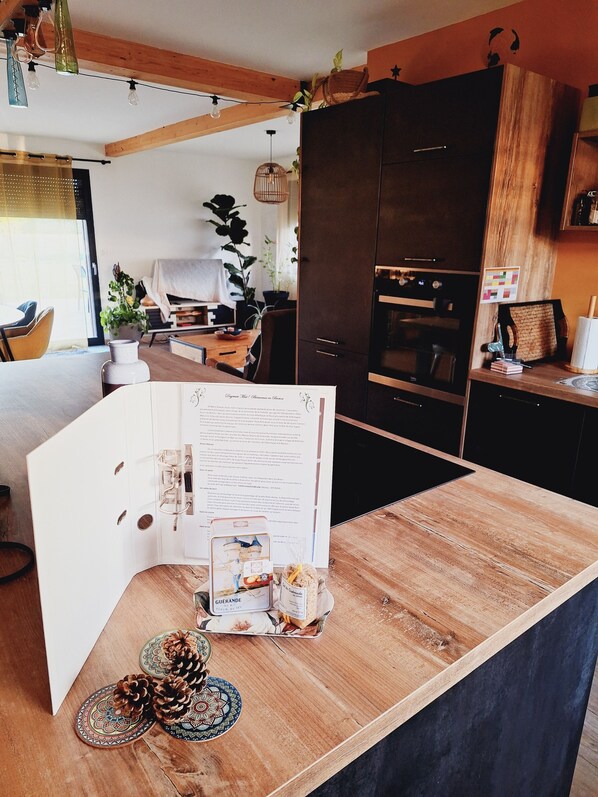 Eine moderne Küche mit Holzschränken, einem eingebauten Backofen und einem Essbereich mit Tisch und Stühlen.