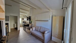 Un salon moderne avec un canapé, un téléviseur et une cuisine en arrière-plan.