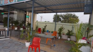 Ein Terrassenbereich im Freien mit Tisch, Stühlen, Topfpflanzen und einer überdachten Sitzgelegenheit.