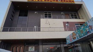 Ein Hotel mit einem Schild, auf dem 'HOTEL RADHA RAMAN' steht, und einem Willkommensschild am Eingang.