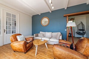 A living room with a sofa, two armchairs, a coffee table, a hanging chair, and a lamp.