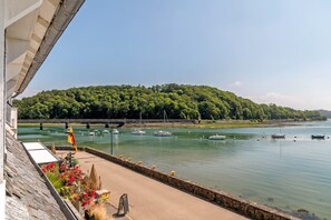 Une vue sur le front de mer, avec des bateaux, un pont et une colline boisée.
