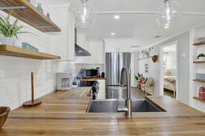 A modern kitchen with wooden countertops, stainless steel appliances, and pendant lighting. - Walking On Sunshine: 2BR Home (Tybee Island)
