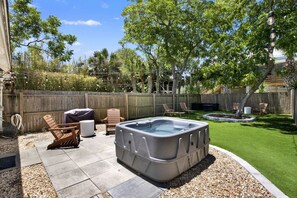 Ein Garten mit Whirlpool, Terrassenmöbeln und einem gepflegten Rasen.