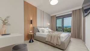 Un dormitorio moderno con cama, mesita de noche, lámpara y vistas al exterior.