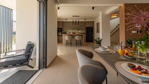 Una cocina moderna con comedor, una escalera y vistas al exterior.