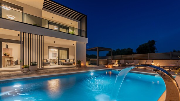 Una casa moderna de dos pisos con piscina, mobiliario exterior y un patio cubierto.