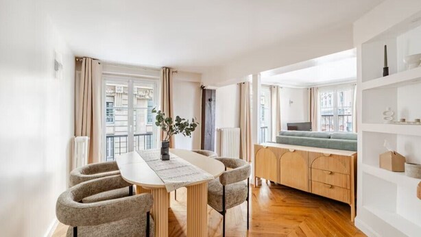 A modern living room with a dining table, chairs, a sofa, and a view of the city. - Palais Royal - Prestige between the Louvre and the Opera (Paris)