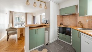 A modern kitchen with green cabinets, a wooden countertop, and a built-in oven. - Palais Royal - Prestige between the Louvre and the Opera (Paris)