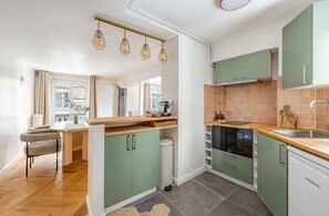 A modern kitchen with green cabinets, a wooden countertop, and a built-in oven. - Palais Royal - Prestige between the Louvre and the Opera (Paris)