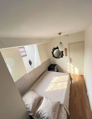 A bedroom with a bed, bedside tables, a mirror, and a door. - Beach RAMBLA (Barcelona)