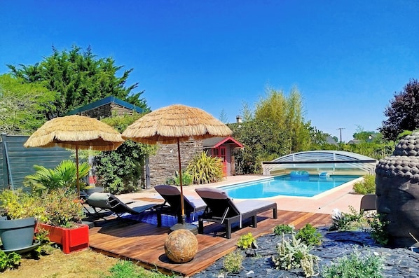 A backyard with a swimming pool, lounge chairs, and a small building with a red roof.
