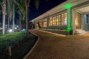 A villa with a paved walkway, large windows, and a sign reading 'Villa do Conde.' - Pousada Villa do Conde (Brotas)