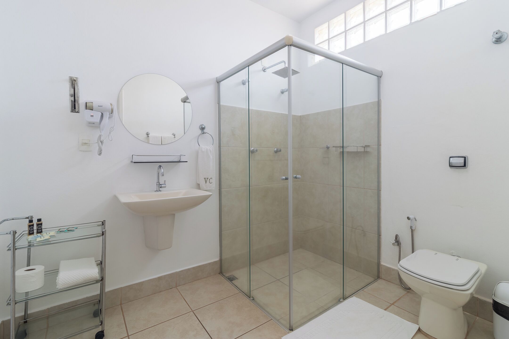 A modern bathroom with a glass-enclosed shower, a sink with a mirror, and a toilet.