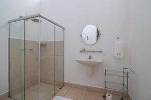 A modern bathroom with a glass shower enclosure, a sink, a mirror, and a towel rack.