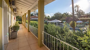 A covered balcony with railings, potted plants, and air conditioning units. - Pousada Villa do Conde (Brotas)
