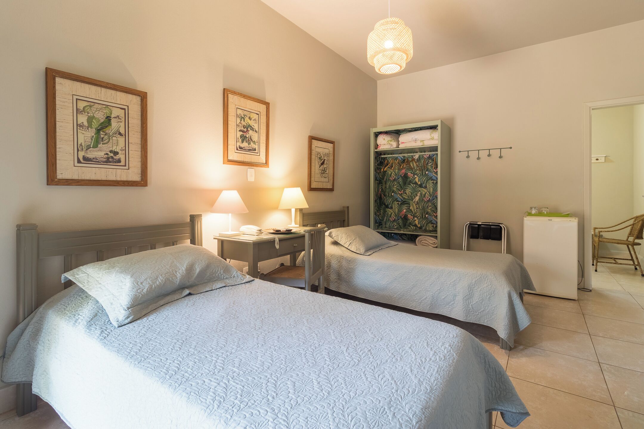 Une chambre d’hôtel avec deux lits, un bureau avec une lampe, une armoire et un réfrigérateur.