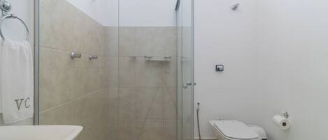 Un baño con ducha de vidrio, bañera blanca, inodoro y toallero con toalla.