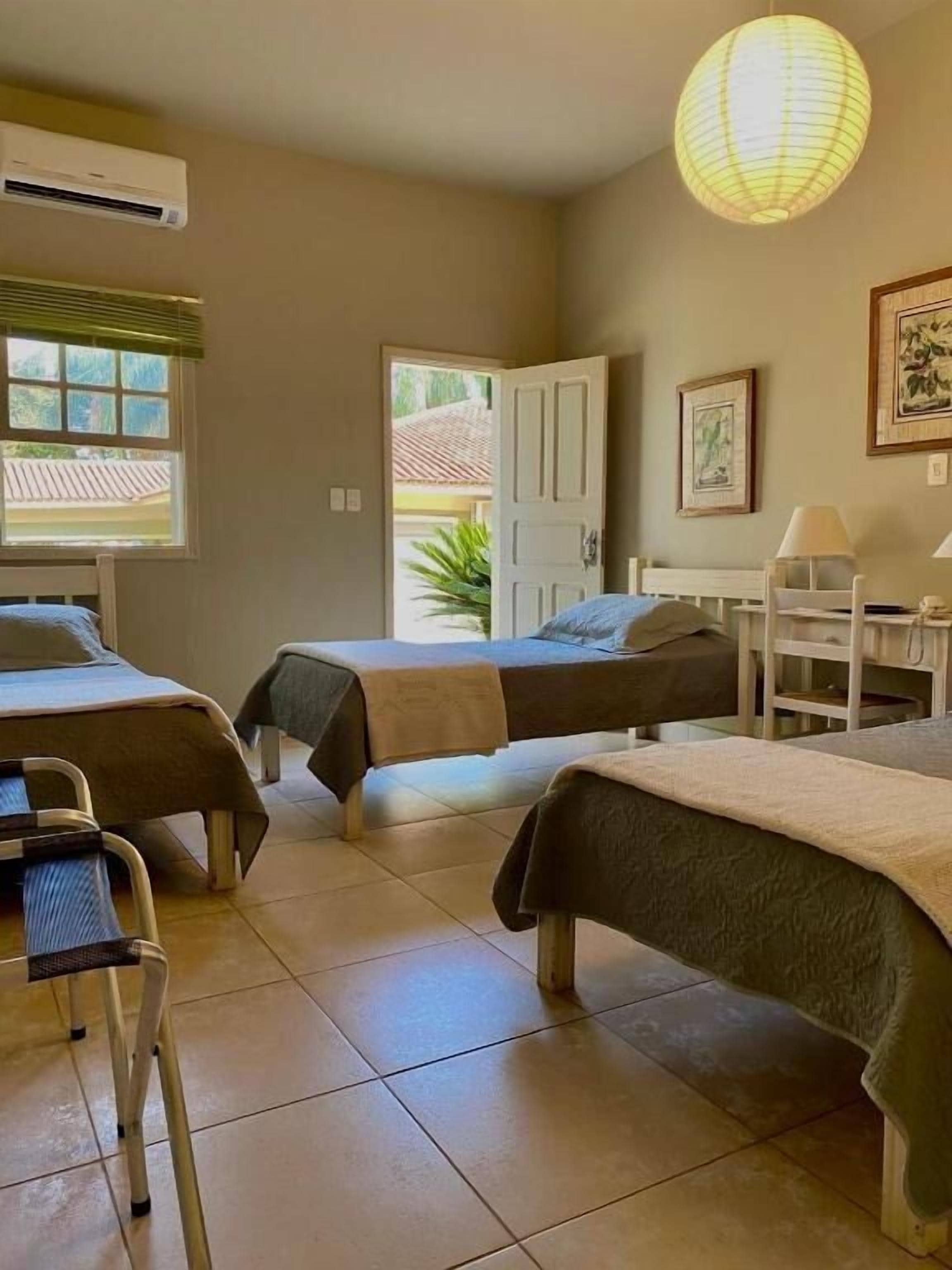 A room with three beds, a desk, a chair, and a standing aid.