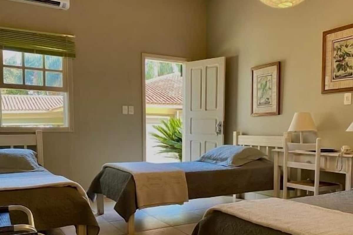 A room with two beds, a desk, a chair, and a wheelchair.